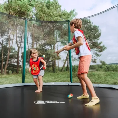 Zwei Kinder und ein Erwachsener spielen auf einem Trampolin am Meer