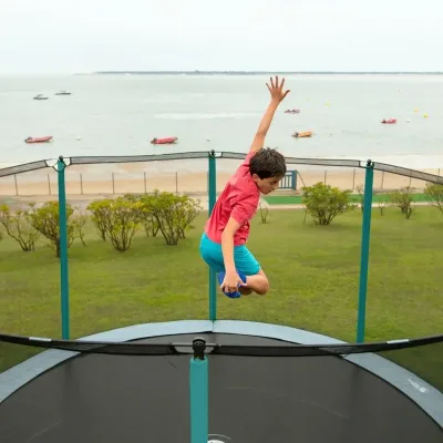Kind springt auf einem Trampolin mit Blick aufs Meer